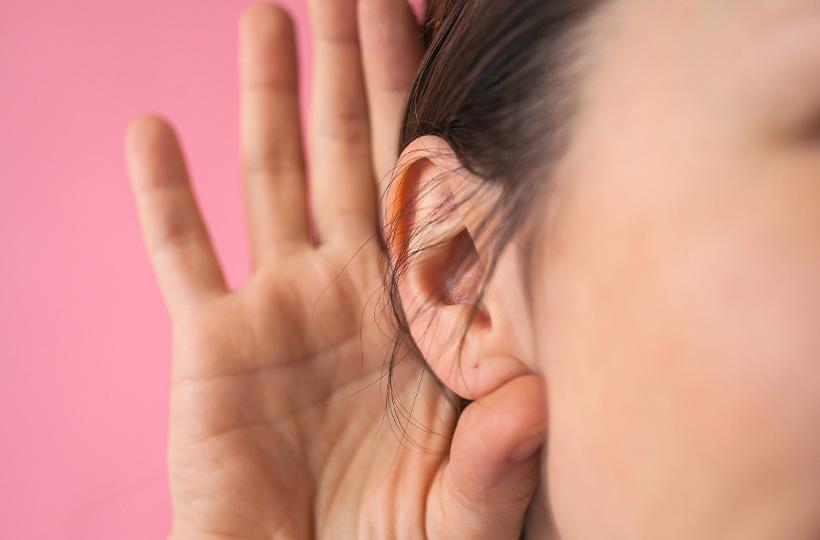 Una mujer se lleva la mano a la oreja para escuchar mejor.